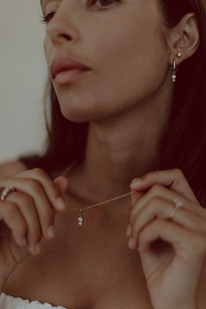 Model wears diamond Therese earrings paired with diamond stud and diamond necklace. 