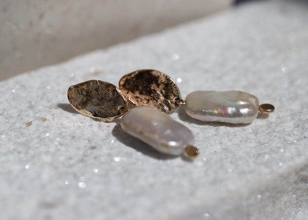 Pearl earring on a textured white surface