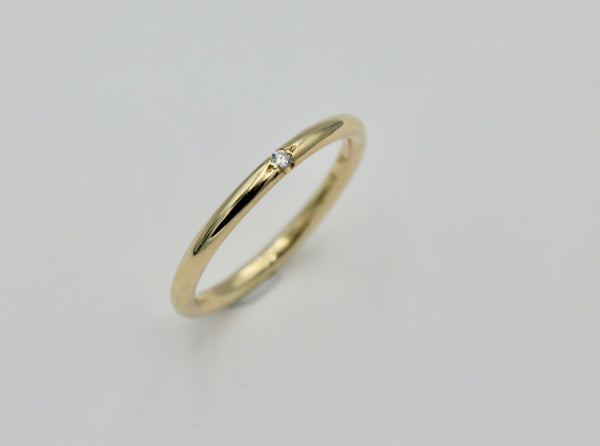 A gold ring with a small round stone set in the center, presented on a white background.