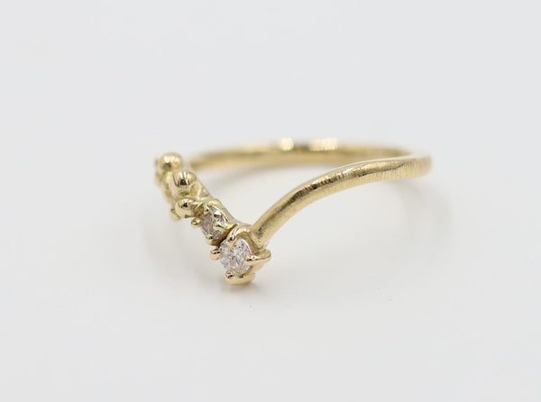A gold-colored, vintage-style diamond ring with beaded detailing and a central diamond, set on a plain background.