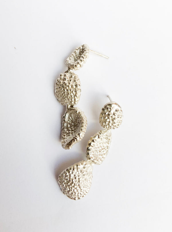 A pair of silver stud-style earrings with a textured surface resembling a wave or scales, approximately 40mm in length.